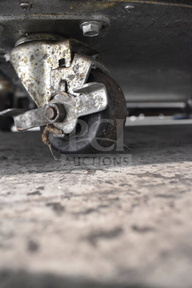 Close-up of a commercial caster from Traulsen RHT132WUT-HHG stainless steel reach-in refrigerator, showing wear.