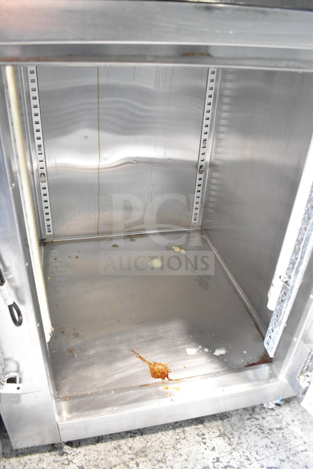 Traulsen RHT132WUT-HHG stainless steel refrigerator, 24.2 cu. ft., glass half door, commercial casters, interior stains visible.