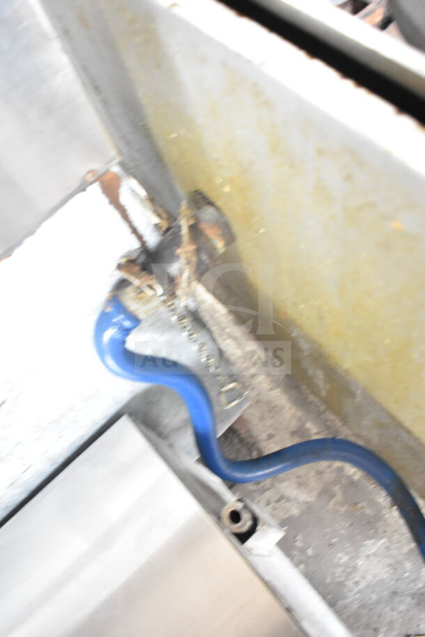Blurry close-up of Vulcan Commercial Floor Style Gas Range connection, showing a blue hose attached to the unit.
