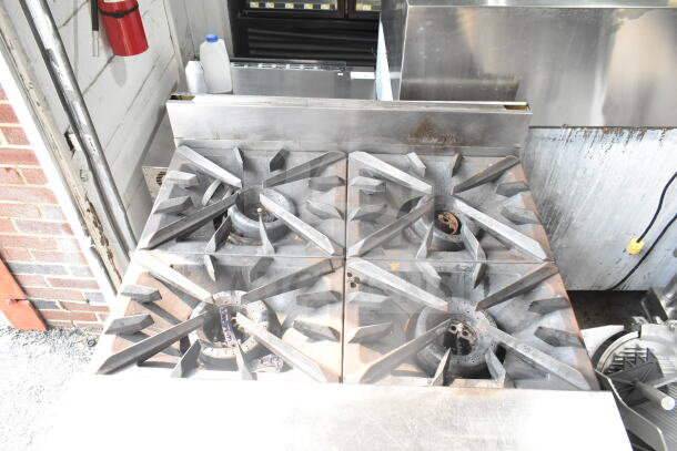 Vulcan commercial gas-powered 4-burner range. Shows heavy-duty cast iron grates, industrial condition. Ideal for restaurants.