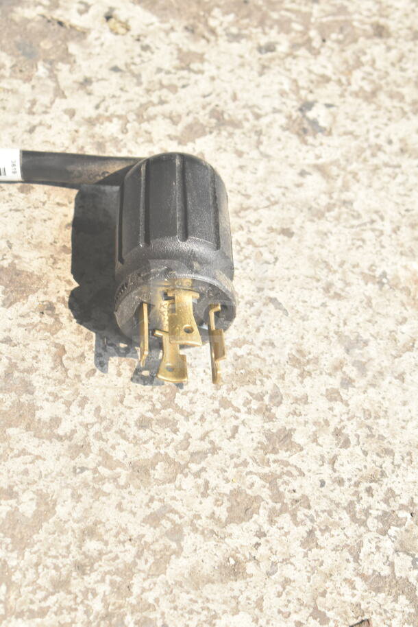 Close-up image of a power plug, possibly for a 2019 True GDM-49F-HC commercial freezer. Black casing with brass prongs.