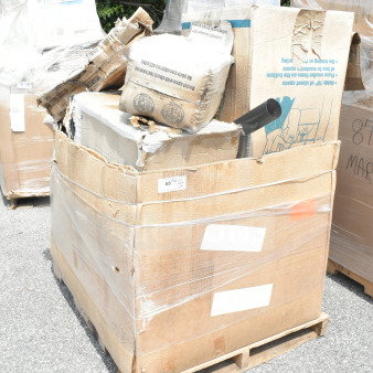 Cardboard box on pallet containing 9 new scratch-and-dent items, including a shelf, pot rack, and grease trap.