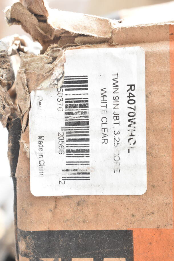 Cardboard box with a partially torn label, showing barcodes and text "R4070WHC, TWIN 9IN JBT, WHITE CLEAR." Signs of wear visible.