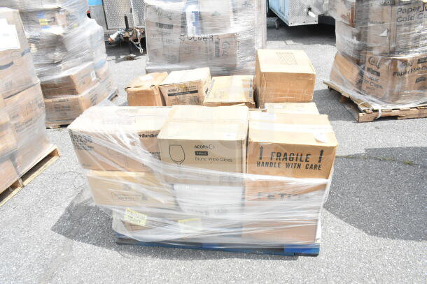 Stack of brand new scratch and dent items on pallet, including bowls, plates, glasses, and a trash can. Box labels indicate fragile and heavy.