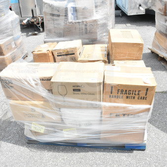 Stack of brand new scratch and dent items on pallet, including bowls, plates, glasses, and a trash can. Box labels indicate fragile and heavy.