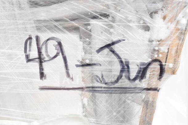 Plastic-wrapped auction items with handwritten label "49-JUN" visible, including gelato pan and hotel pans. Scratch and dent condition.