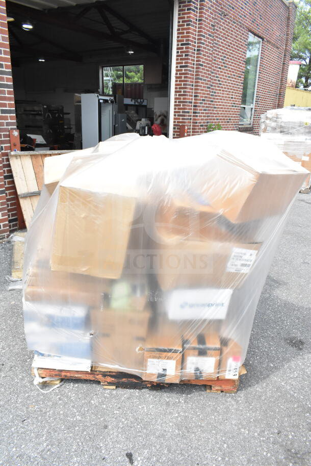 Pallet with 35 brand new scratch and dent items, including plates and baking sheets, wrapped in plastic outside a brick building.