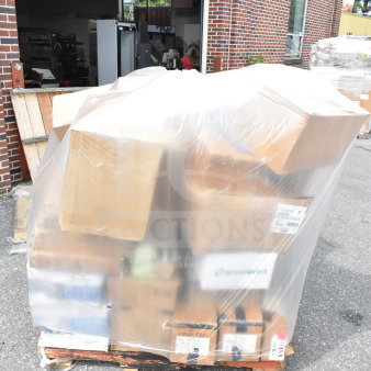 Pallet with 35 brand new scratch and dent items, including plates and baking sheets, wrapped in plastic outside a brick building.