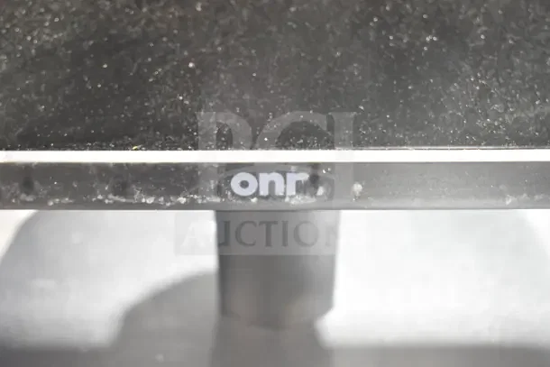 Alt text: "Close-up of Onn monitor base, showing the Onn logo. Dust visible on the surface."