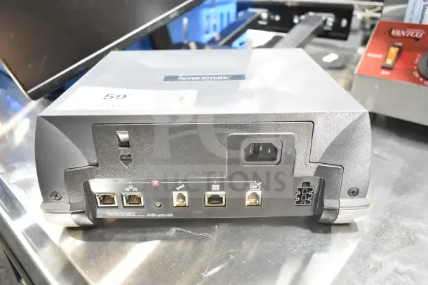 Sensormatic AMB-9010-IPS unit with ports and power input, showing a label "59". Includes Onn monitor and Tripp Lite bracket, 7 items total.