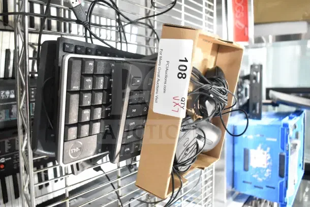 Box of 7 used computer keyboards and mice with cables on a metal shelf; tag reads "108 QTY VX7".