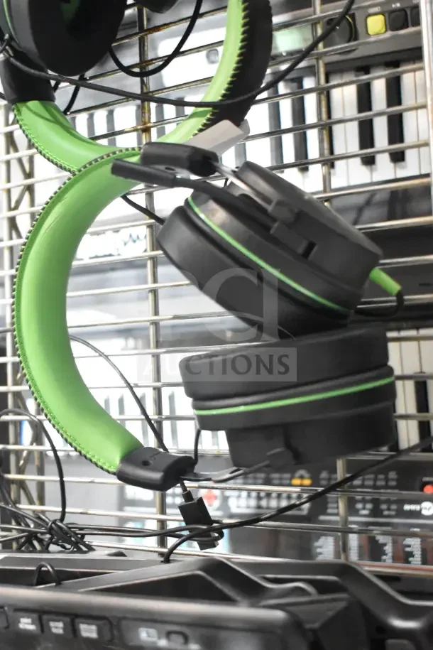 Two black and green over-ear headphones with cushioned ear pads, hanging on a wire rack, appearing in good condition.