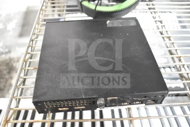 Black Neatgear box on metal rack, showing wear. Includes ports on side. Auction item part of 2 various items lot.