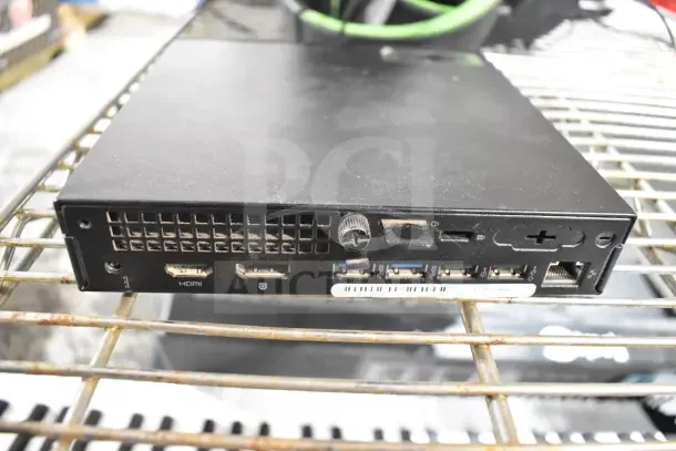 Black Neatgear network box with multiple HDMI, USB, and Ethernet ports on a wire rack, signs of wear visible.