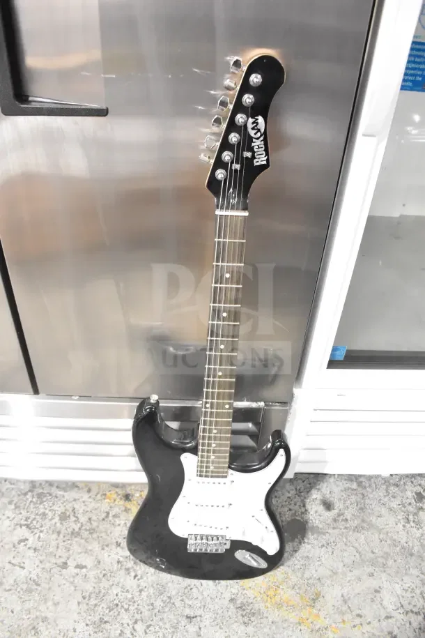 Black Rock Jam electric guitar, six strings, glossy finish, white pickguard, chrome tuning pegs, used condition.