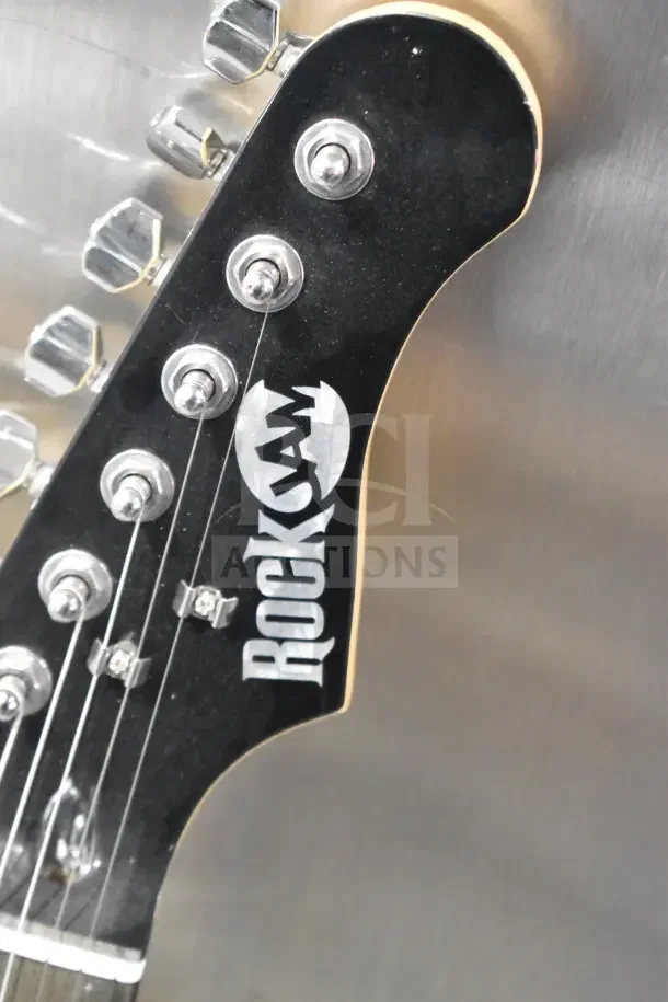 Headstock of a Rock Jam guitar with chrome tuning pegs. The guitar is in good condition, featuring the Rock Jam logo.