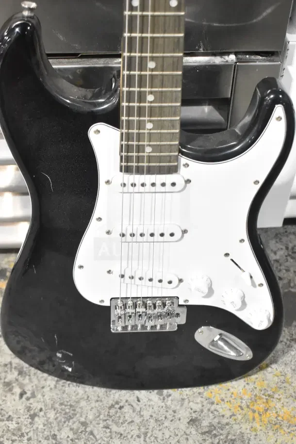 Black Rock Jam electric guitar with white pickguard, three single-coil pickups, and volume/tone knobs, showing minor wear.