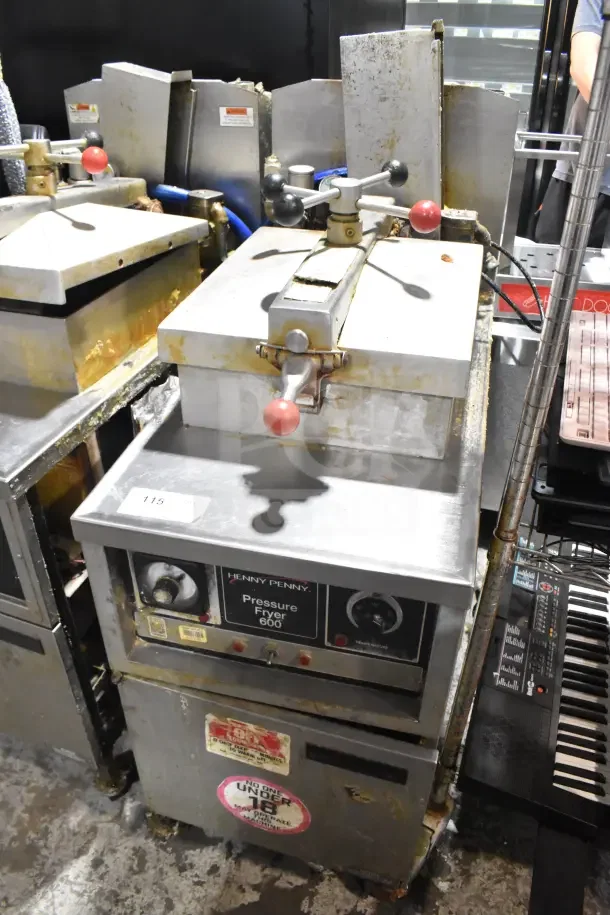 Henny Penny 600 Commercial Pressure Fryer, natural gas, 80,000 BTU, on casters, visible wear, model and warning labels present.