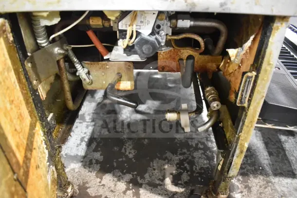 Henny Penny 600 pressure fryer, natural gas powered, 80,000 BTU, on casters. Visible pipes and wires, shows signs of wear.