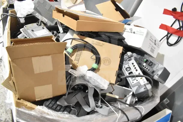 Pallet lot with computer keyboard, Sensormatic ZBSMPROE, assorted electronics, cables, and open cardboard boxes.