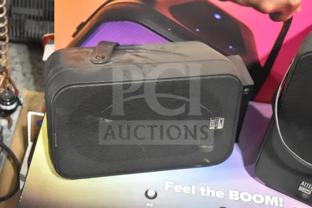 Store display with two black Altec Lansing speakers, featuring a mesh front and visible branding. Slight wear noted.