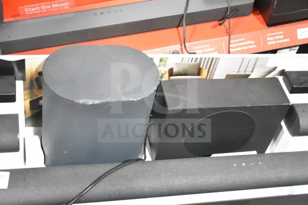 Store display with an assortment of Onn sound bars and speakers, showcasing various models and conditions. Tags indicate features.
