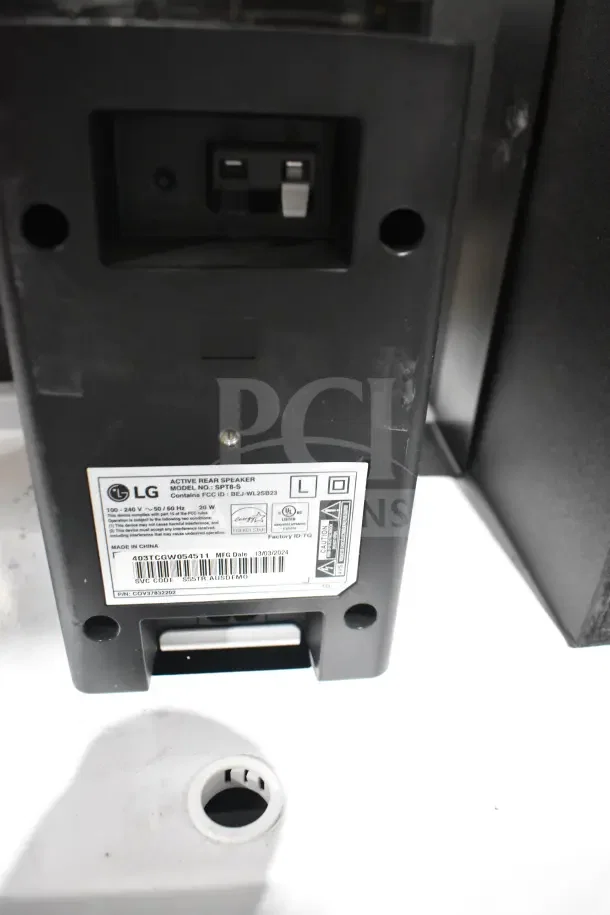 LG Active Rear Speaker, Model SPT5-S, shown in store display. Labels indicate power specs and manufacturing details.