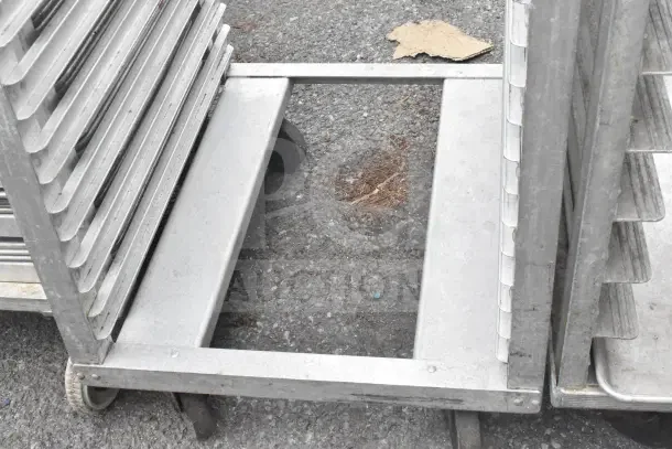 2 commercial pan transport racks on metal casters, used condition, sturdy metal construction, ideal for kitchen storage.