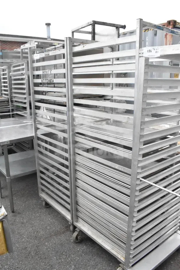Two commercial pan transport racks on casters, includes 40 baking pans. Good condition, ideal for large kitchens.