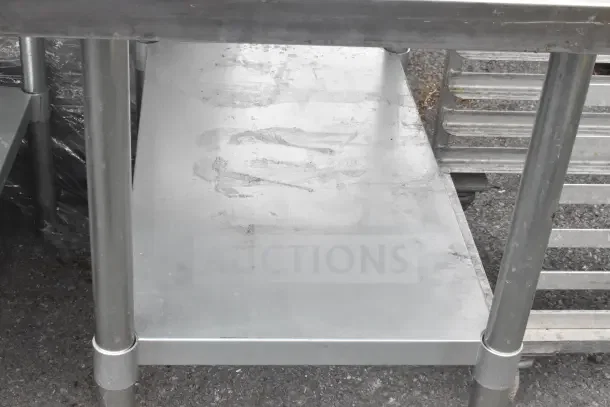 Commercial metal table with under shelf, sturdy build, used condition, ideal for kitchens or workshops.