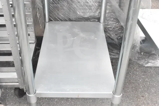 Commercial metal table with under shelf, featuring sturdy construction and light wear. Ideal for industrial use.