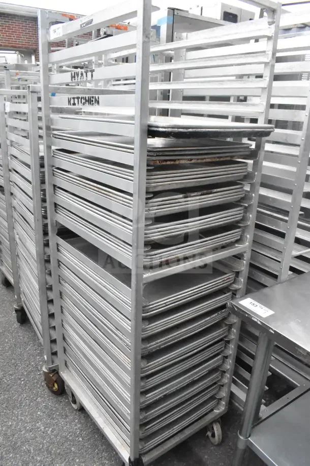Two commercial pan transport racks with 56 baking pans included. Marked "Hyatt Kitchen." Good condition.