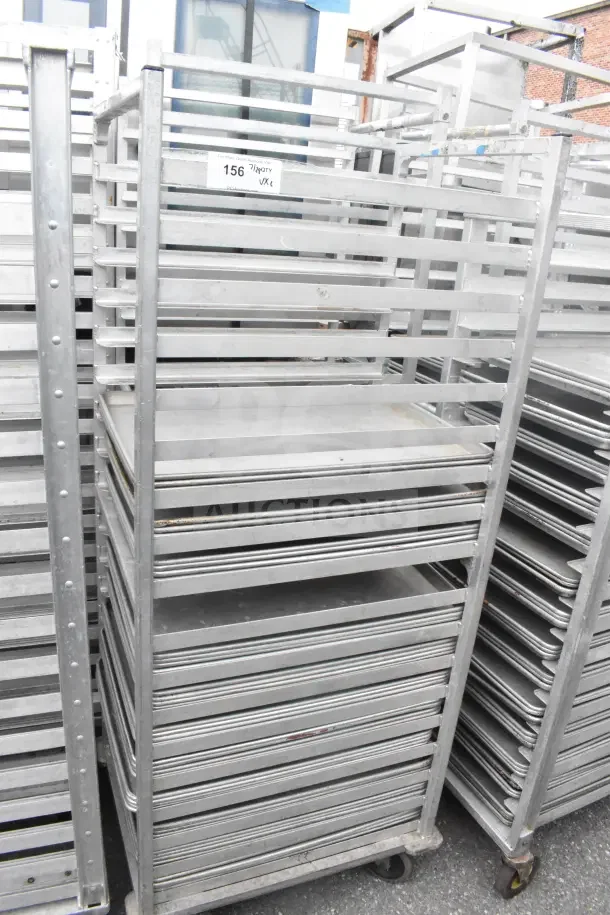 2 commercial pan transport racks with 44 baking pans in good condition. Includes visible tag with auction details.