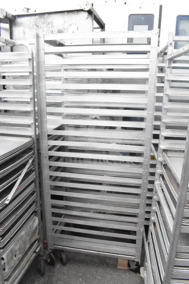 Two commercial pan transport racks, metal construction, used condition, multiple shelving levels, rolling casters for mobility.