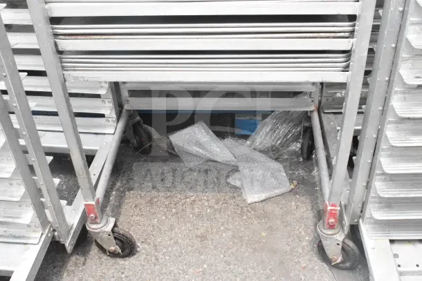 2 commercial pan transport racks with 68 baking pans. Sturdy metal frames, caster wheels, ideal for bakery use.