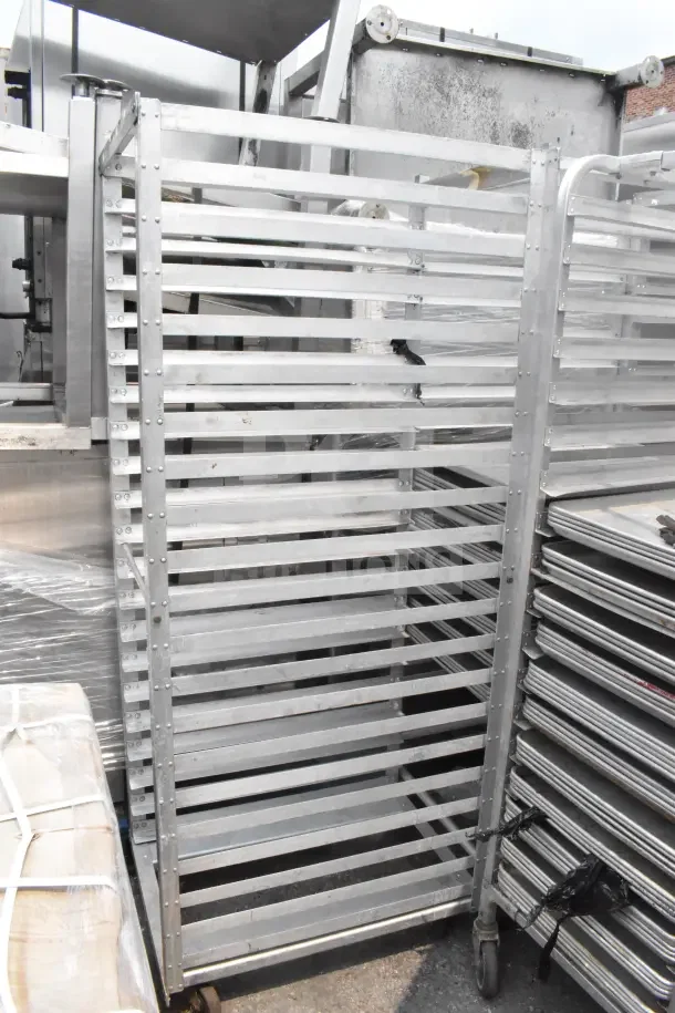 Two commercial pan transport racks with multiple shelves, metal construction, on casters for mobility, good condition.