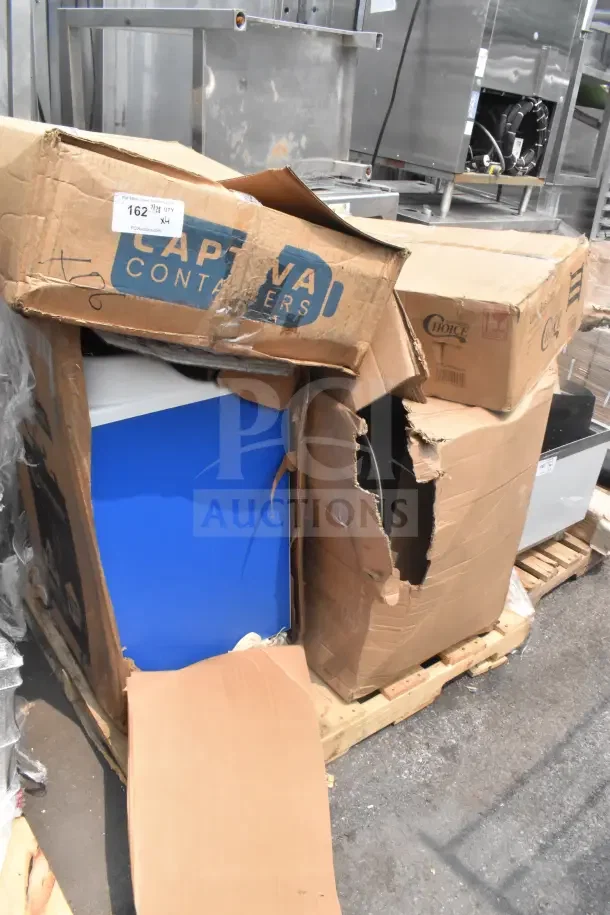 Cardboard boxes with minor damage containing new items including an exhaust fan and bussing cart on a pallet.