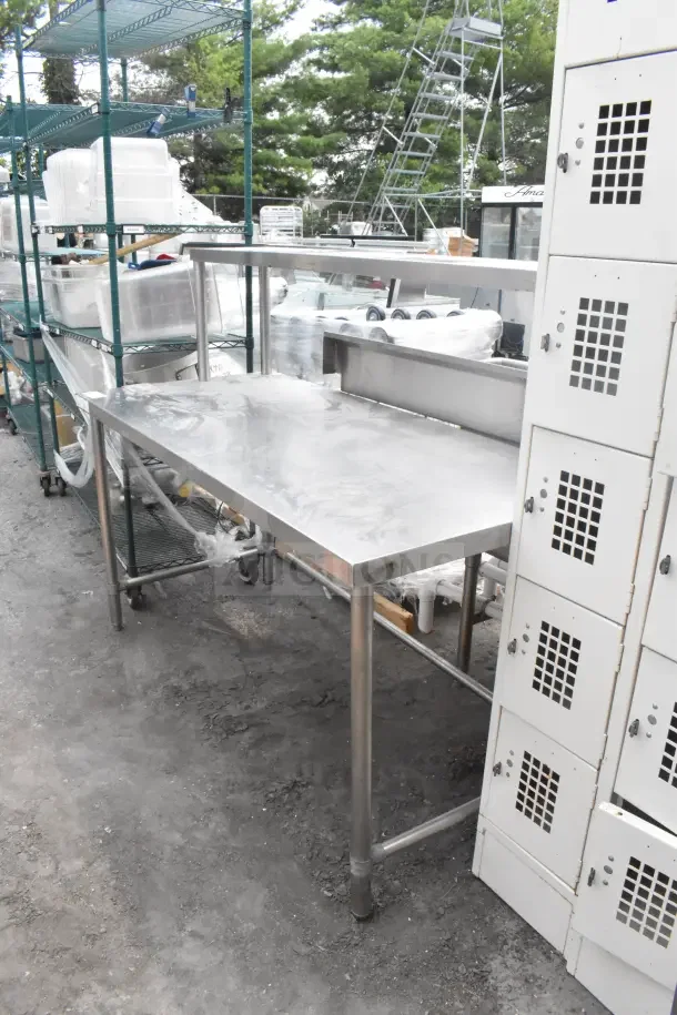 Stainless steel table with over shelf, sturdy condition, ideal for kitchens or workshops, visible on concrete floor.