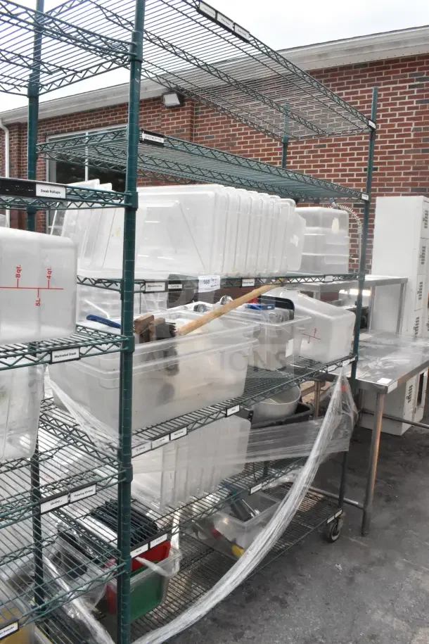 Green 5-tier wire shelving unit on commercial casters, includes bins, labels visible, outdoor setting, dismantling required for buyer.