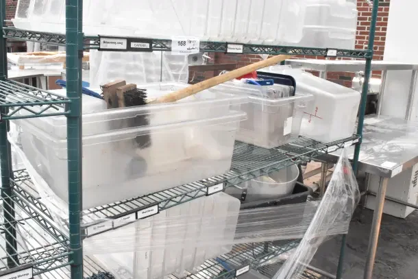 Green finish 5-tier wire shelving unit on commercial casters with contents including bins. Tags and labels visible.