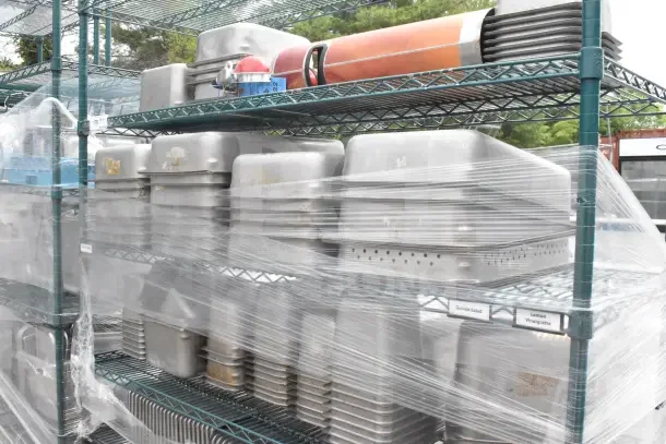 Green 6-tier wire shelving unit on casters, wrapped with contents. Includes drop-in bins. Buyer disassembly required.