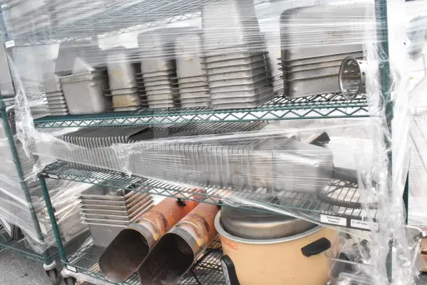 Green 6-tier wire shelving unit on commercial casters with contents including drop-in bins; requires dismantling for shipping.