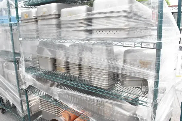 6-tier wire shelving unit with green finish on commercial casters, wrapped in plastic, includes metal drop-in bins.