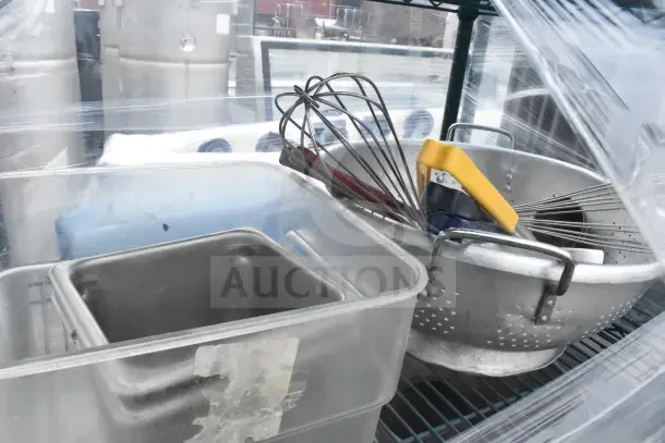 Green 6-tier wire shelving unit on casters with utensils, colander. Buyer must dismantle, shipping not provided.