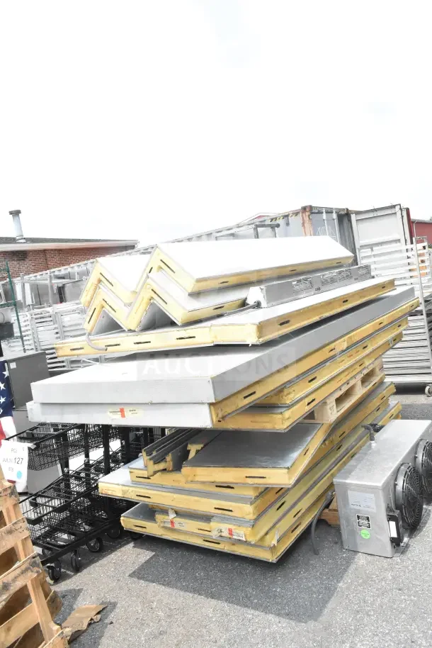 Walk-in box panels and evaporator fan on pallets; metal construction, fair condition, some visible wear and tear.