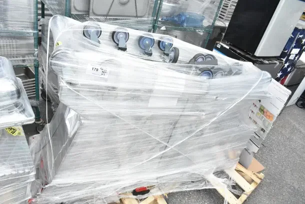 5 brand new scratch and dent Regency supermarket shopping carts, 6.3 cu. ft., wrapped on a pallet. Visible labels and wheels.