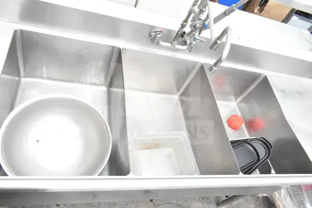 Commercial 3 bay sink with dual drain boards, stainless steel, includes fixtures, used condition, visible scratches.