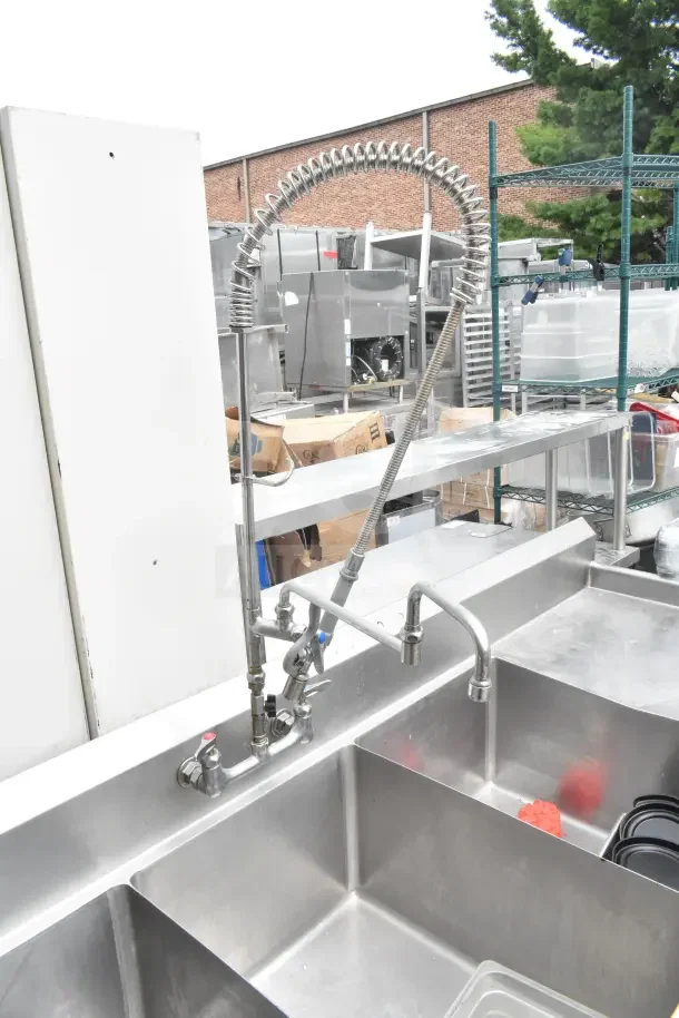 Commercial 3 bay stainless steel sink with dual drain boards and high-arc faucet. Ideal for restaurants. Good condition.