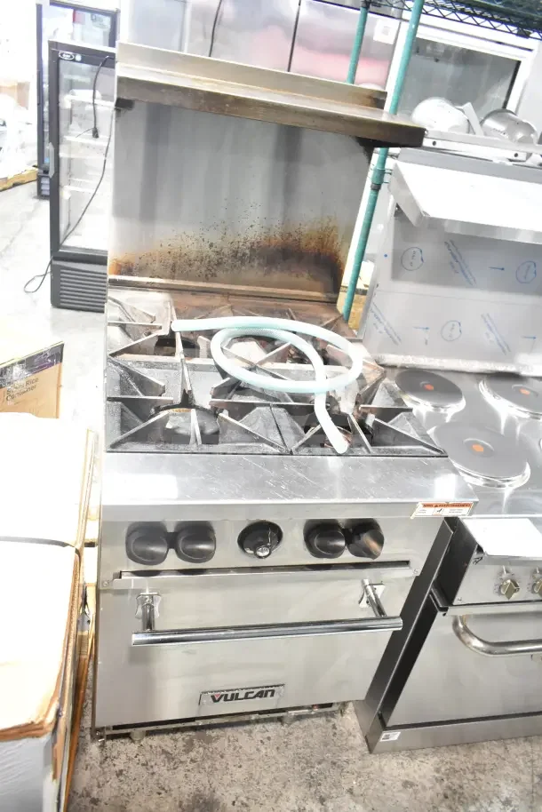 Vulcan commercial gas 4-burner range with oven, over shelf, and backsplash. Visible signs of use.