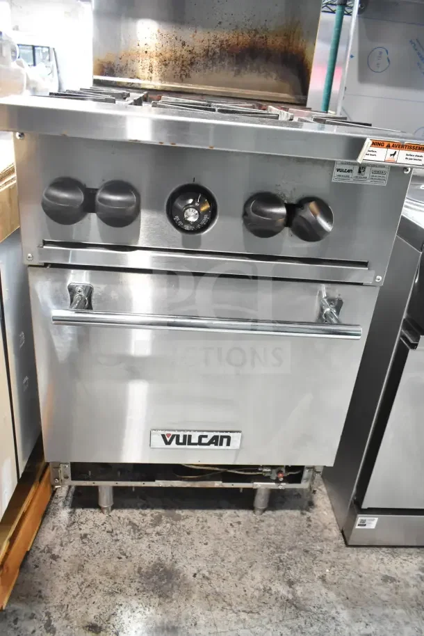 Vulcan Commercial Gas 4 Burner Range with oven, over shelf, and backsplash. Features control knobs and Vulcan logo. Used condition.